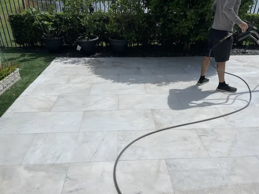 Pressure washing white pavers by a pool