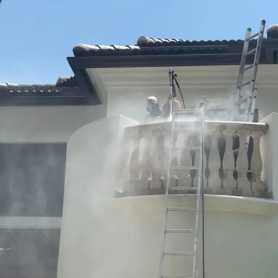 Pressure washing a second-floor balcony from a ladder