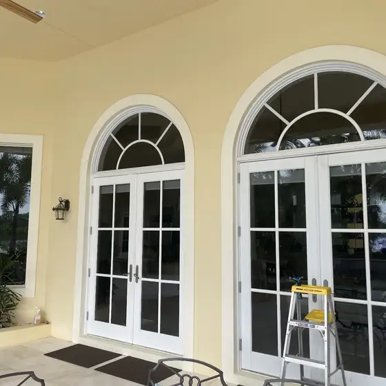 Arched French doors on a covered patio with a step ladder at the glass