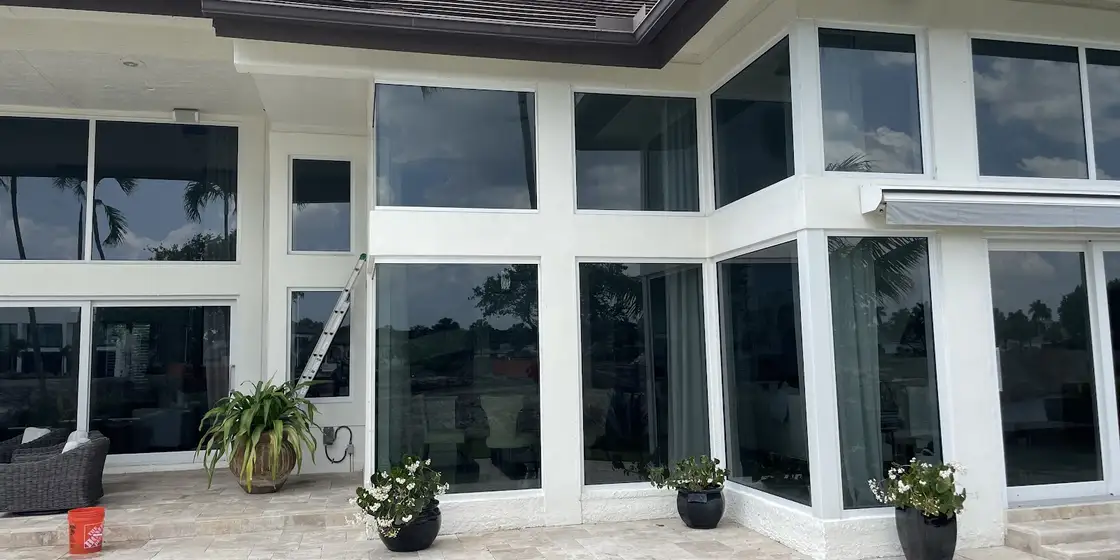 Modern home with walls of glass above a stone patio