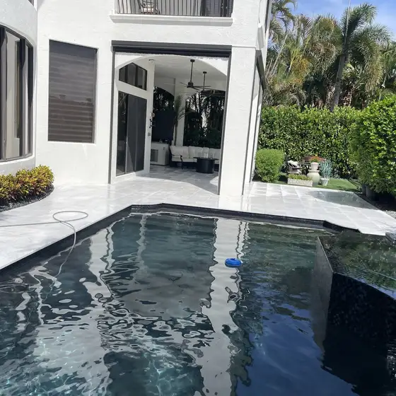 Dark-bottom pool and white deck under a covered terrace