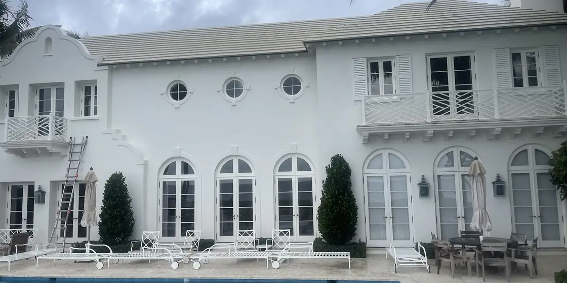 White two-storey home behind the pool