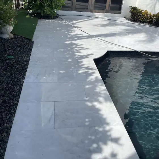 White stone walkway running along the pool