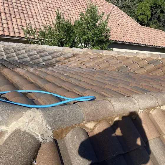Barrel tile roof mid-clean, the worker's shadow on the tile