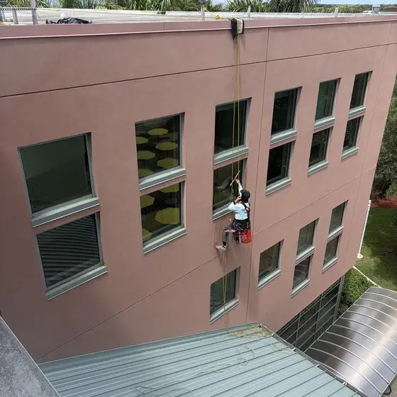 Window cleaner on a rope, three storeys up a building wall